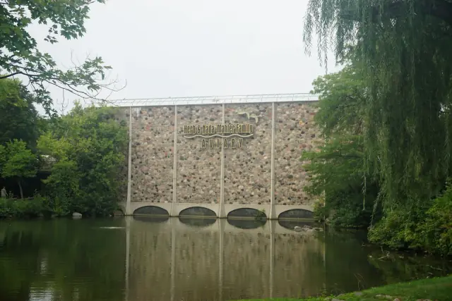 The real Milwaukee County Zoo aviary building beside a pond and trees