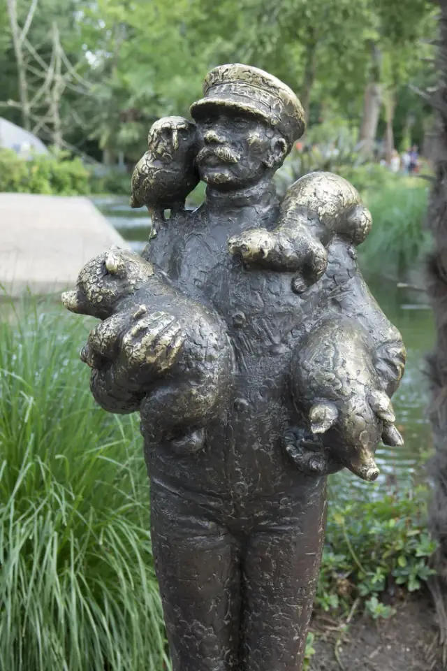 A bronze sculpture of a zookeeper with animals in a landscaped zoo